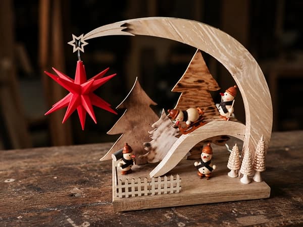 Festlicher Holzbogen mit Tannen, Winterfiguren, Schlitten und rotem Stern
