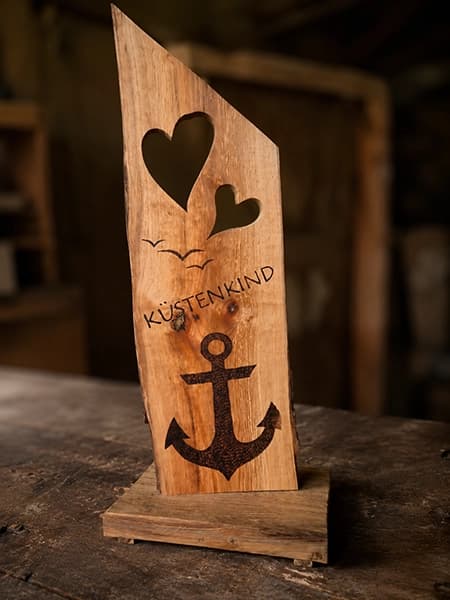 Holzvase mit getrockneten Gräsern auf einer alten Holzbank